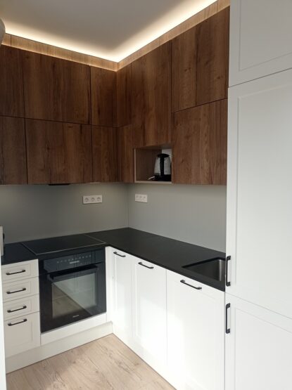 Ez a konyha első ránézésre modern konyhabútor látszatát kelti, azonban közebbről nézve észrevehető a klasszikus konyhabútorokra jellemző marásminta is a fehér ajtókon.